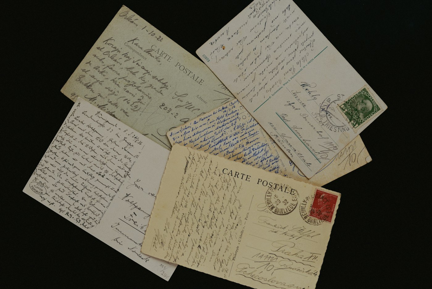 A scatter of handwritten postcards on a black ground