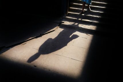 A long shadow stretching across sunlit pavement in hard light